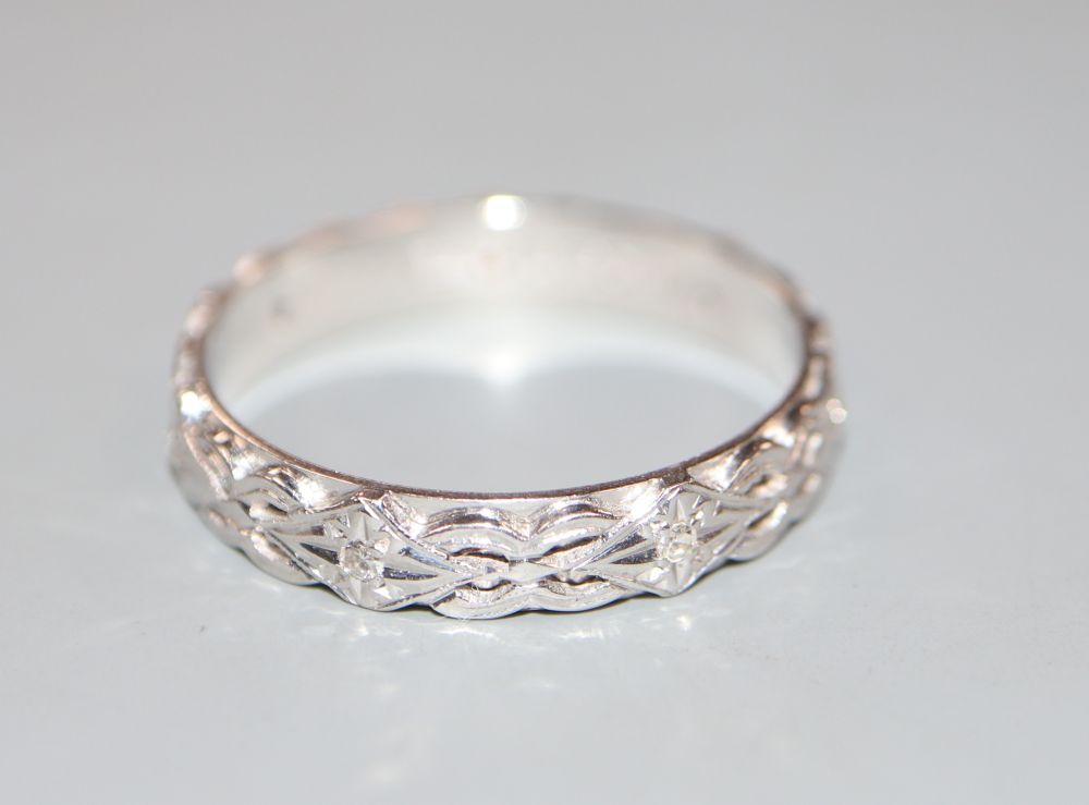 A modern bright cut engraved 18ct white gold and diamond chip set eternity ring, size V/W, gross 5.2 grams.